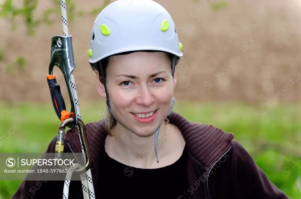Young woman with a climbing rope wearing a safety helmet