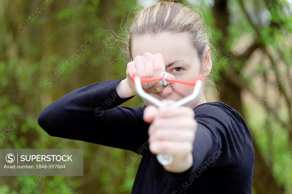 Young woman aiming a catapult, slingshot
