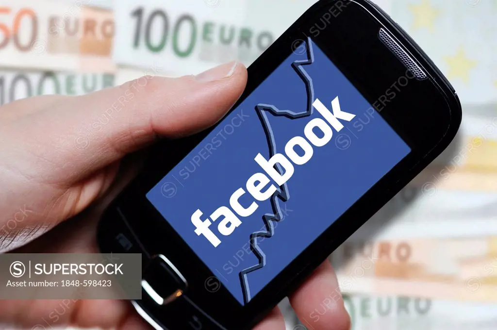 Hand holding a smartphone with a Facebook logo in front of euro notes, symbolic image for the Facebook IPO