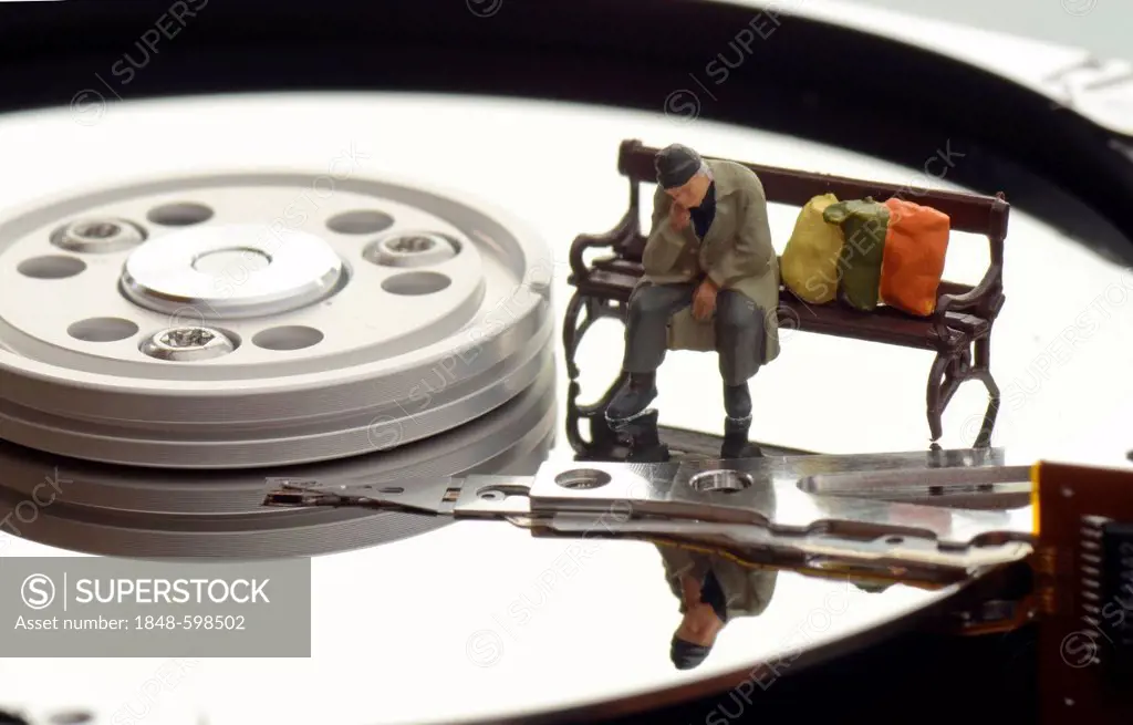 Miniature figure of a homeless person sitting on a bench on a hard drive, symbolic image for cluttered data