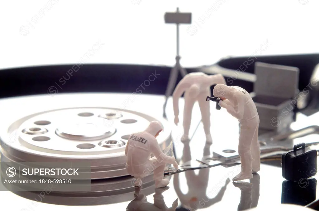 Miniature figures of a police forensic team on a hard drive, symbolic image for data theft or piracy