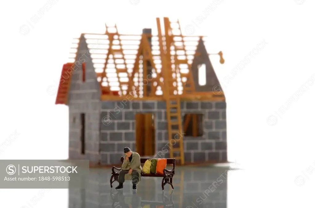 Miniature figure of a homeless person sitting on a bench in front of a unfinished house under construction, symbolic image of poverty due to high cons...