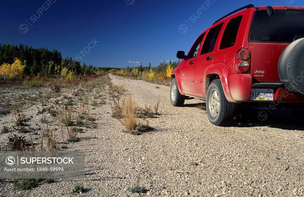 Red fourwheeldrive on a dirt road, Northwest Territories, Canada