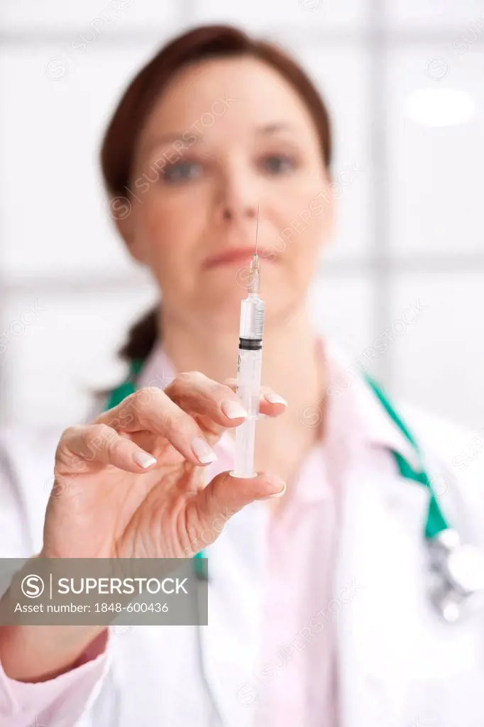 Doctor holding a syringe in her hand, checking it