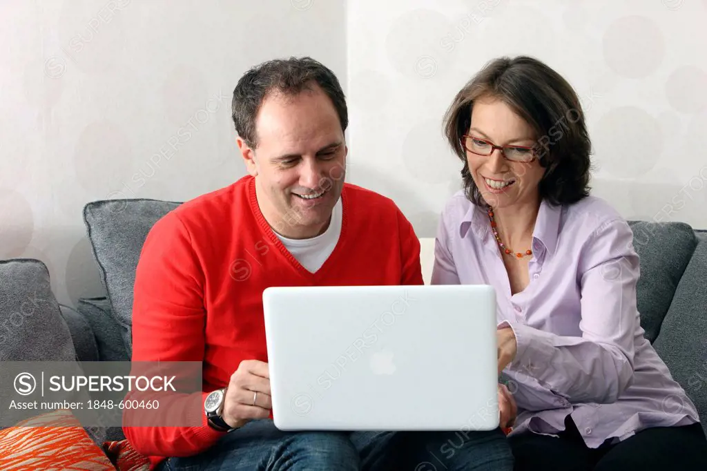 Couple, man, woman, about 45 years old, surfing the Internet on a laptop at home