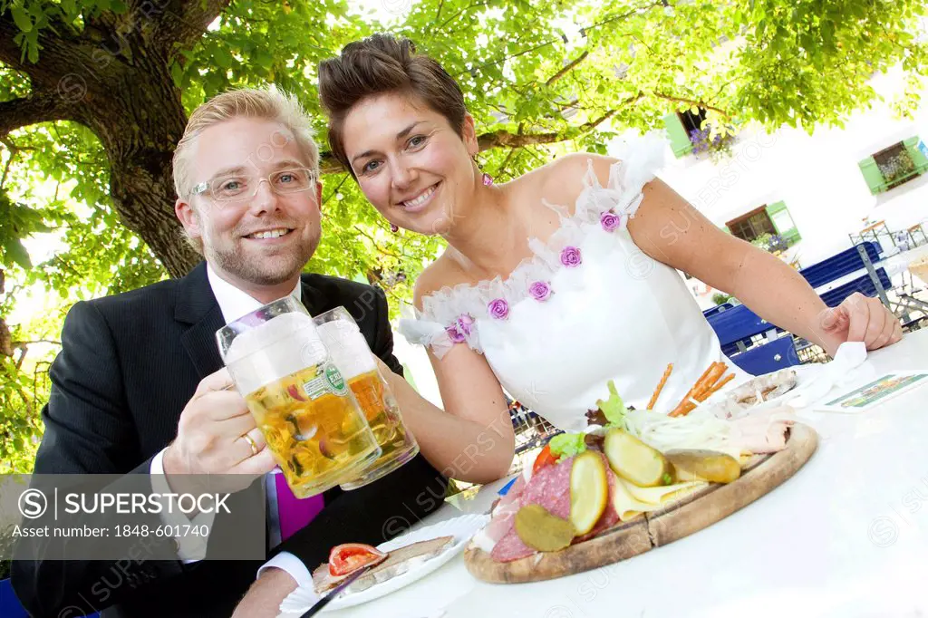 Bridal couple having a light meal and drinking beer in a Bavarian beer garden, Regensburg, Bavaria, Germany, Europe