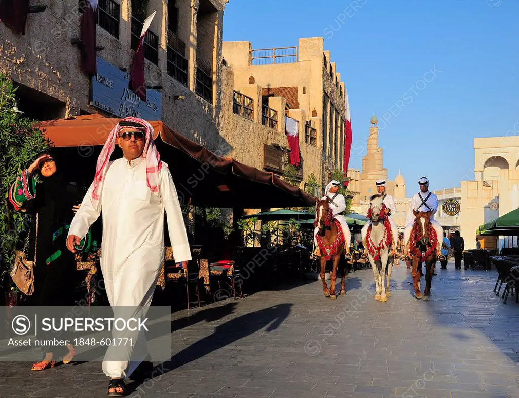 Man wearing a traditional Thobe and mounted police in front of the tower of the Islamic Cultural Centre FANAR, Souk Waqif, Doha, Qatar, Middle East