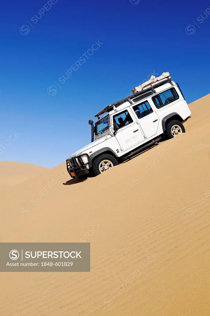 Landrover Defender off-road vehicle driving down a huge dune, Namib-Naukluft National Park, Skeleton Coast National Park, Namib Desert, Namibia, Afric...