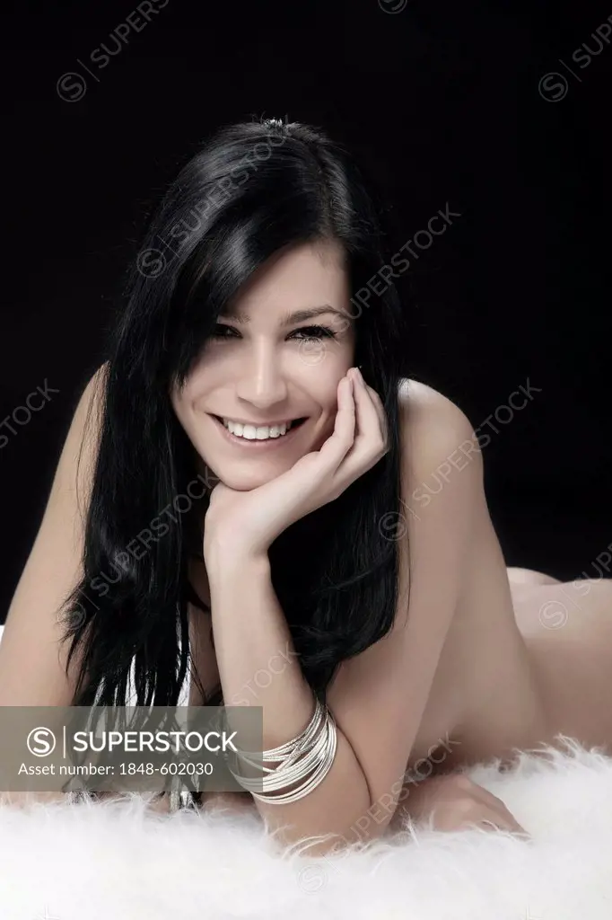 Naked young woman lying on white fur, beauty shot