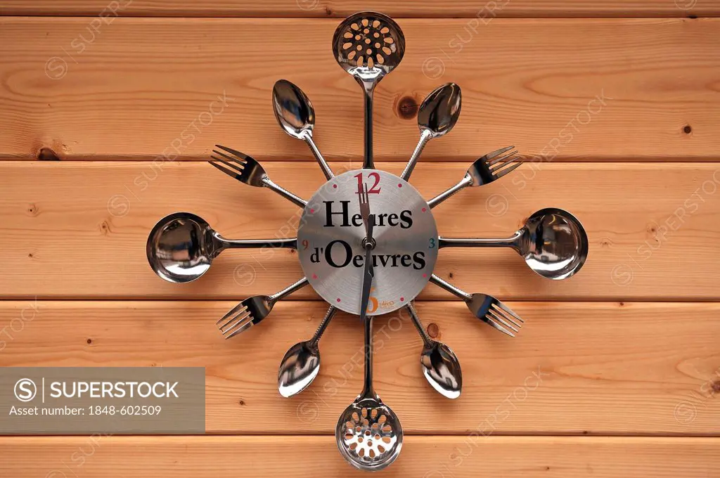 Wall clock made of cutlery on a wooden wall