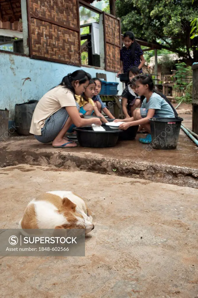 Girls washing dishes outdoors at a well in the Mae La refugee camp, Tak province, Thailand, Asia
