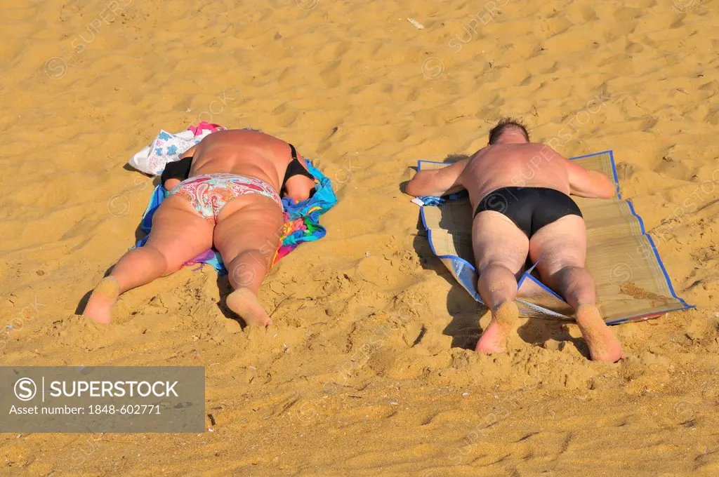 Obese couple sunbathing on a sandy beach, Negombo, Sri Lanka, South Asia, Asia