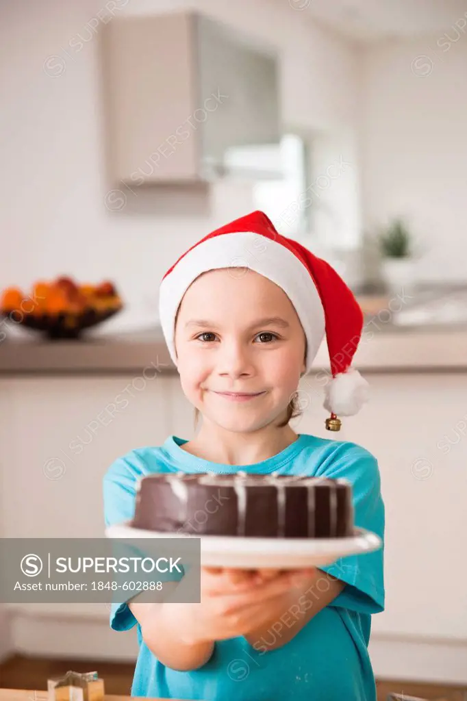 Girl with Santa Claus hat presenting a chocolate cake
