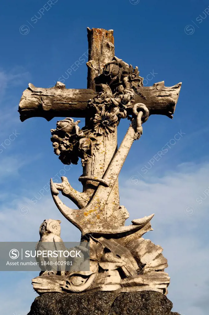 Stone cross with flowers, anchor and an owl, 19th Century, against a blue sky in the cemetery of Guebwiller, Route de Colmar, Guebwiller, Alsace, Fran...