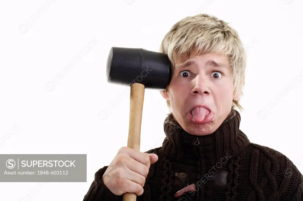 Young man sticking out his tongue and holding a rubber mallet to his temple