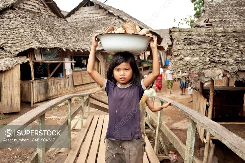 A girl carries a bowl with dried tobacco leaves in the Mae La refugee camp, Tak province, Thailand, Asia