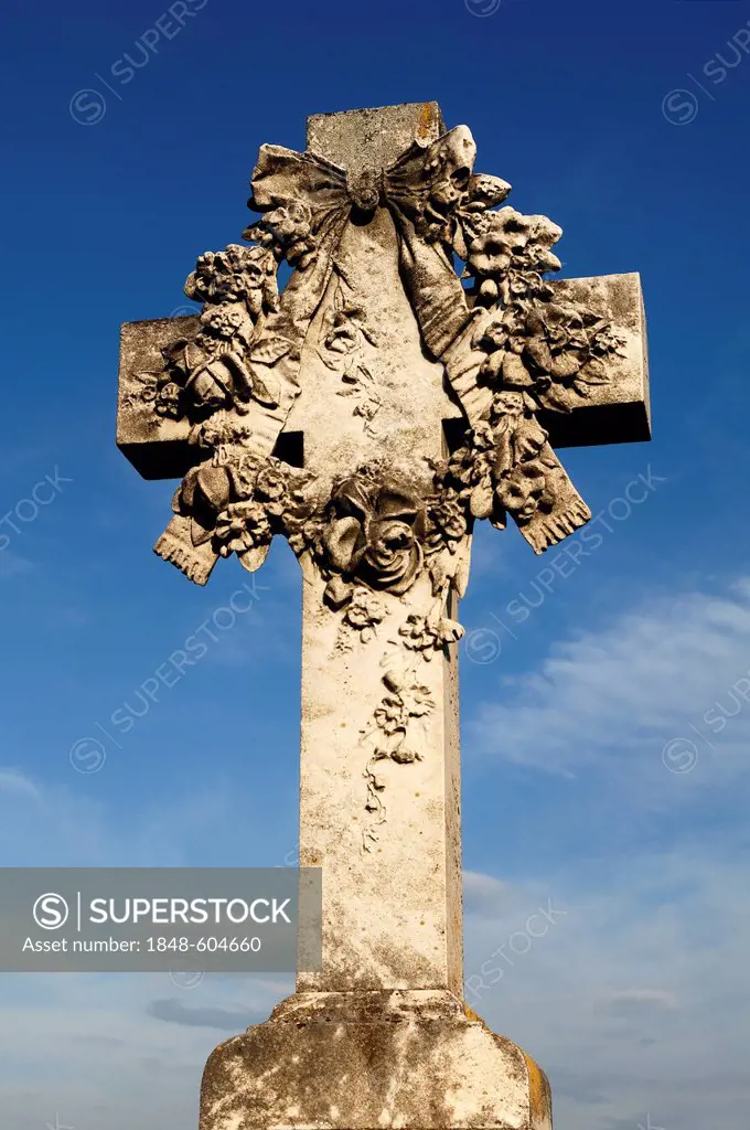 Stone cross with flowers, 19th Century, against a blue sky in the cemetery of Guebwiller, Route de Colmar, Guebwiller, Alsace, France, Europe