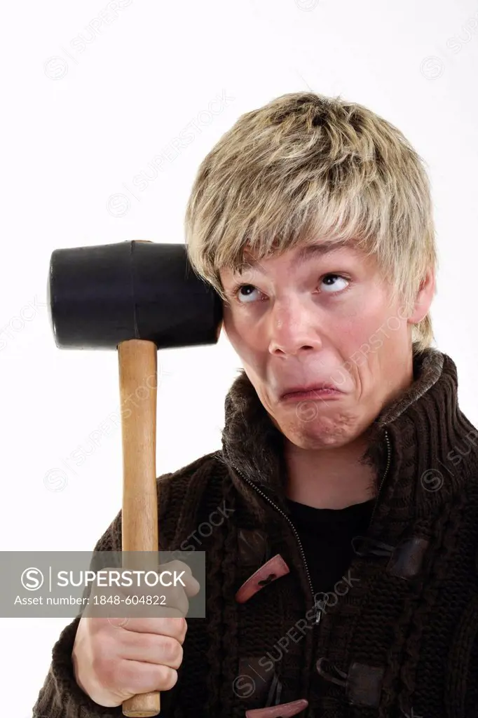 Young man with a strange expression holding a rubber mallet to his temple