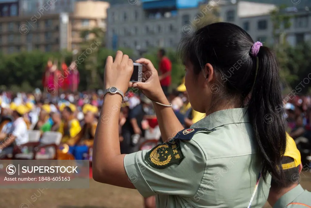 Police officer in uniform photographing at an ethnic festival, Jiangcheng, Pu'er City, Yunnan Province, People's Republic of China, Southeast Asia, As...