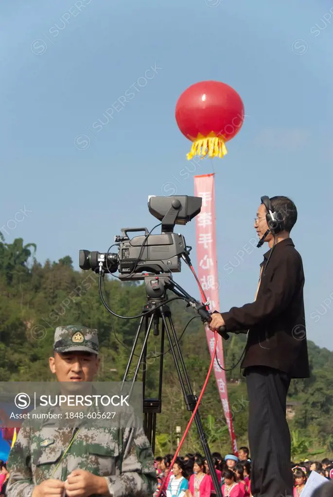 Censorship, censoring the press, a soldier guarding in front of a cameraman with a television camera, TV broadcast of a festival, Jiangcheng, Pu'er Ci...