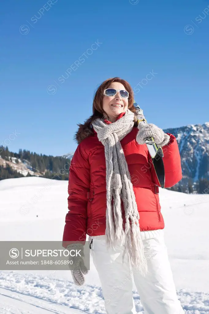 Woman carrying cross-country skis on shoulder in the mountains