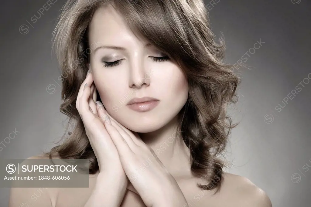 Young woman holding her hands next to her cheek, beauty shot, portrait