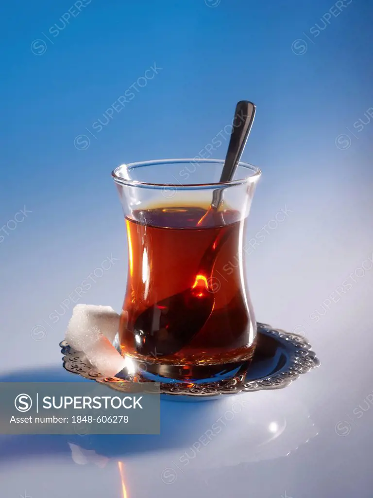 A glass of Turkish tea with sugar cubes and a spoon