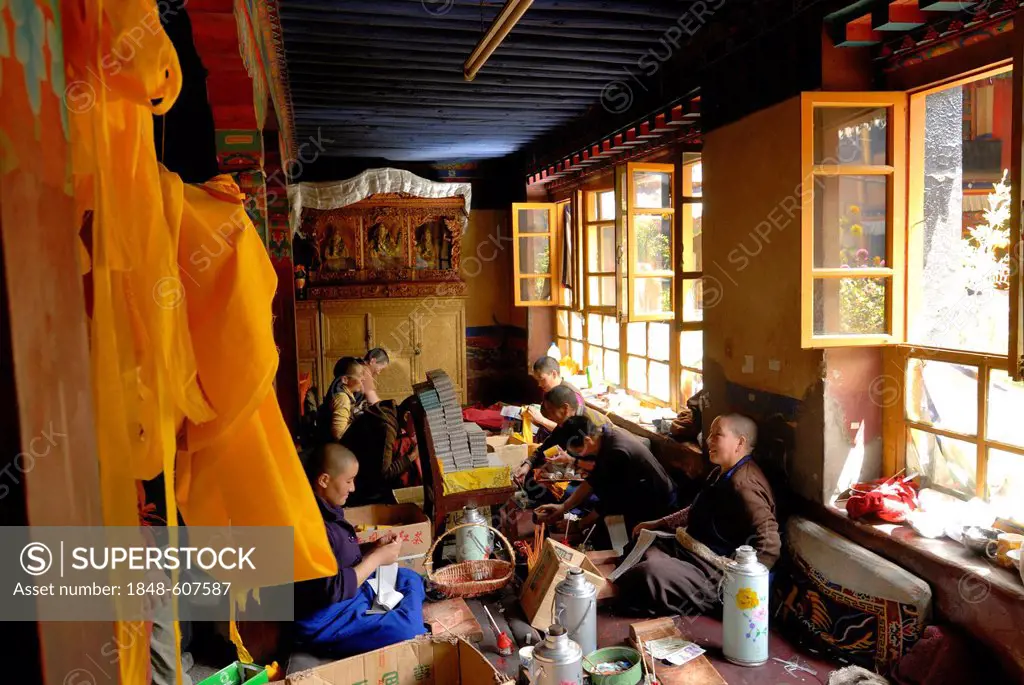 Tibetan nuns sitting in the nunnery of Ani Tsakum, Ani Tsakung, at work and preparing the texts for the filling of Tibetan prayer wheels, prayer-cylin...