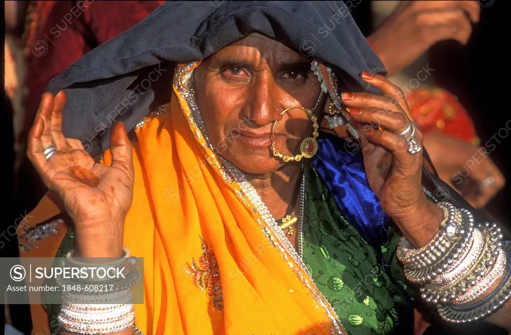 Portrait of an elderly Indian woman wearing traditional dress with a nose ring and bracelets of gold and silver, Thar Desert, Pushkar, Rajasthan, Nort...