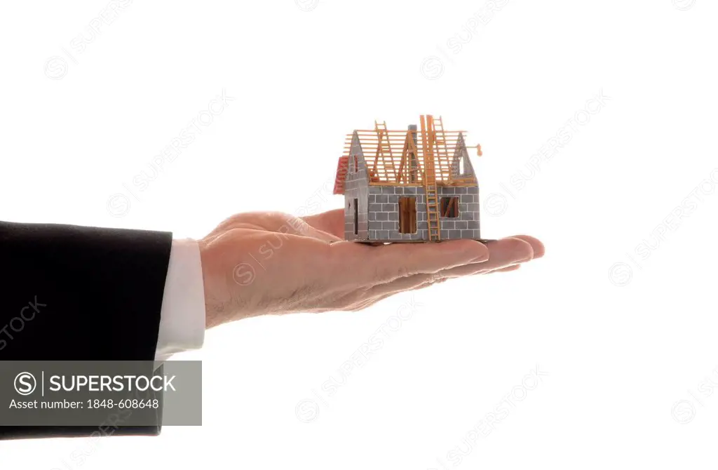 Man's hand holding a model of a house, symbolic image for mortgages