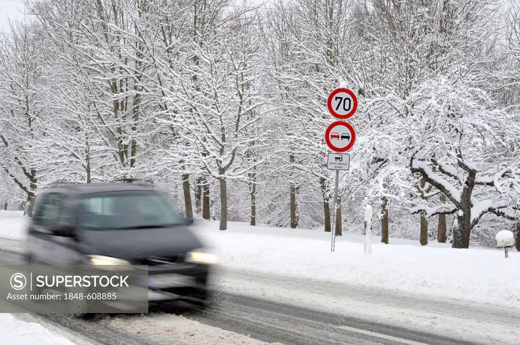 Car on a snow-covered road in winter, slip hazard, warning sign, prohibition sign, blur