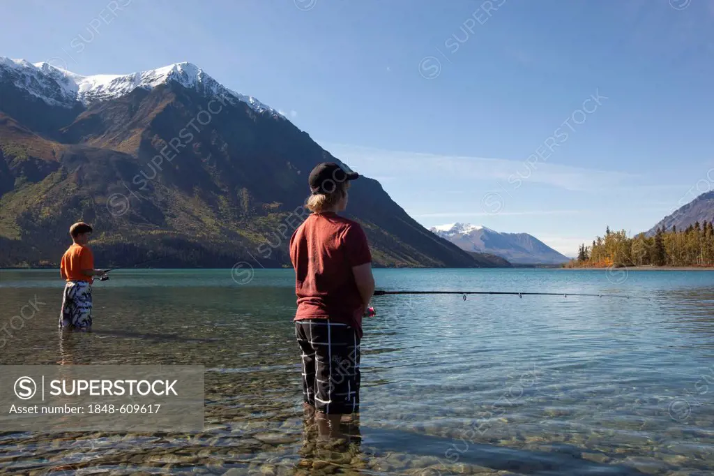 Children, young boys, standing in shallow water, fishing at Kathleen Lake, King's Throne behind, St. Elias Mountains, Kluane National Park and Reserve...
