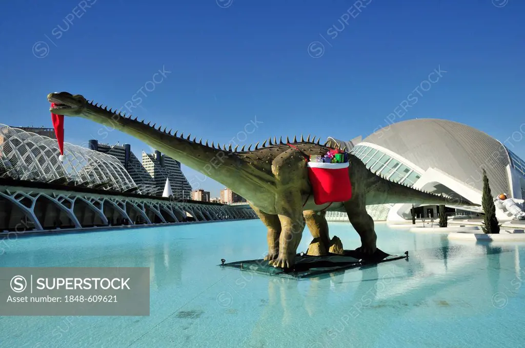 Dinosaur bearing Christmas presents standing in front of L'Hemisferic, Imax cinema and planetarium, Ciudad de las Artes y las Ciencias, City of Arts a...