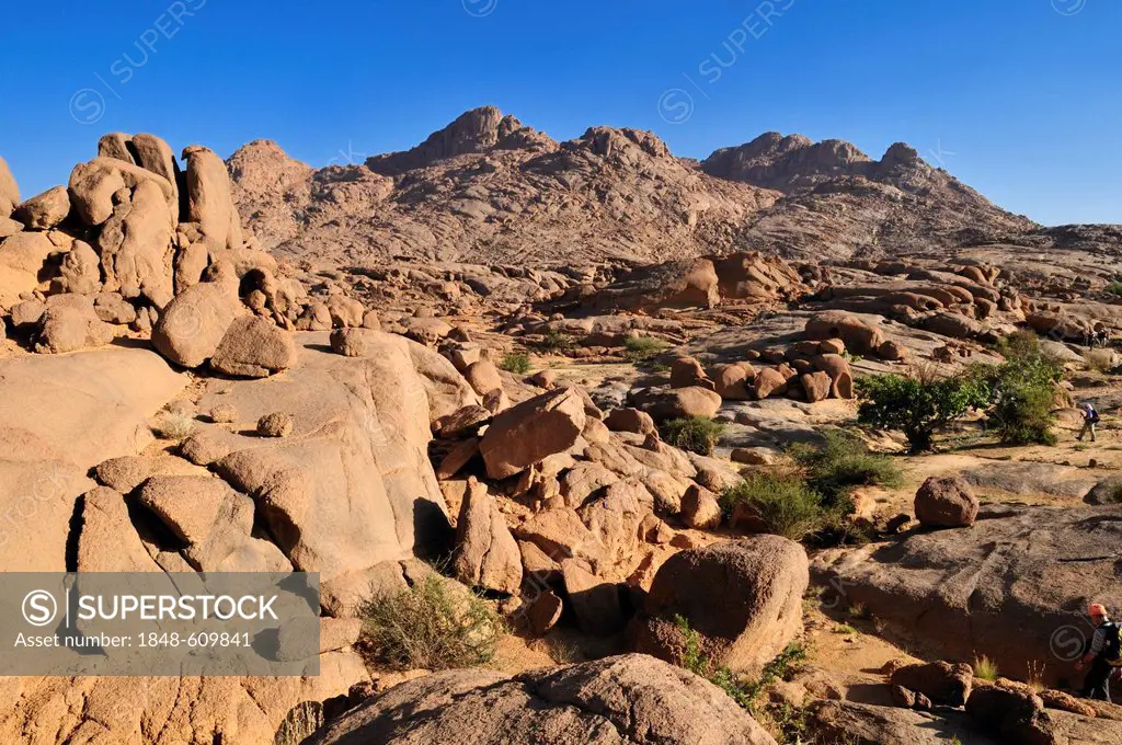 Group of tourists hiking through granite landscape, Hoggar, Ahaggar Mountains, Wilaya Tamanrasset, Algeria, Sahara, North Africa