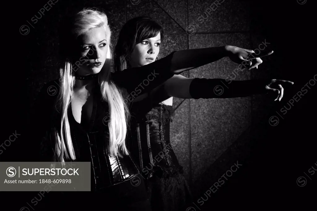 Women dressed in a Goth style, standing pointing their fingers, seriously