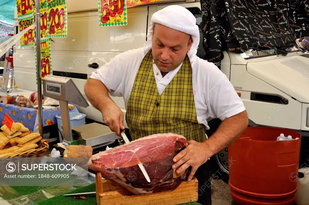 Seller with Italian ham or Prosciuto at a specialties stand on the farmers market, Rome, Lazio, Italy, Europe