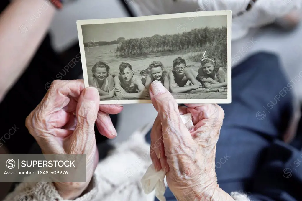 Viewing old photo, old lady's hands holding a historic black and white photography from 1940's, memories, historical photo, portrait, nursing home, re...