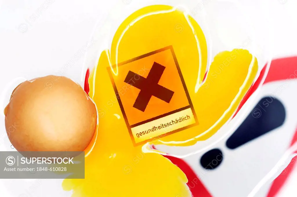 Cracked egg with a warning sign in the yolk, symbolic image for dioxin contamination in chicken eggs
