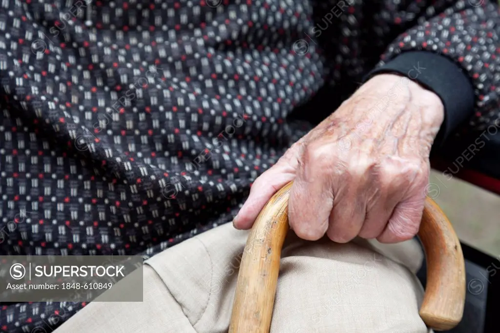 Hand of an elderly man holding a walking stick