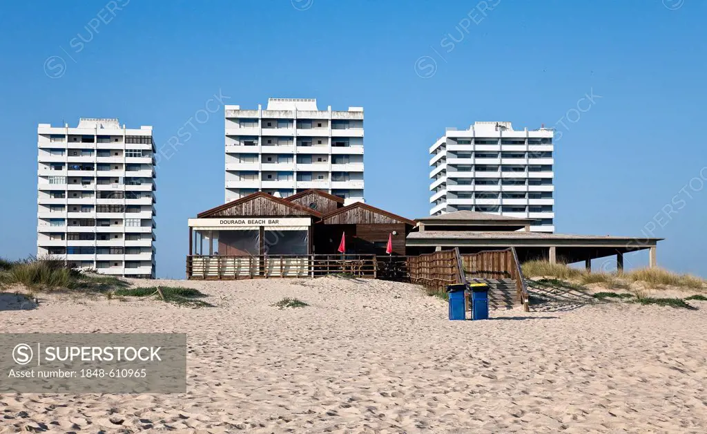 Beach bar, apartment towers at the back, unfinished buildings on the beach of Alvor, Algarve region, Portugal, Europe