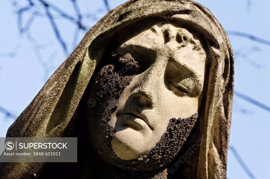 Face of a grieving woman with her eyes closed, weathered historic grave sculpture, Nordfriedhof Cemetery, Duesseldorf, North Rhine-Westphalia, Germany...