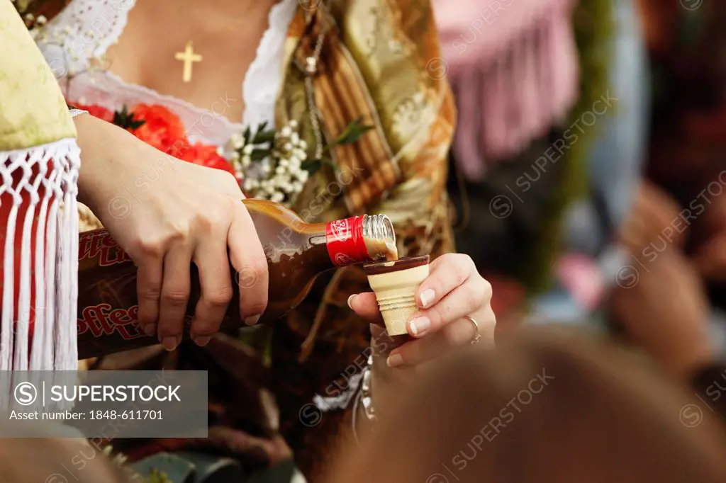 Woman pouring a shot of liquor, Leonhardi procession, Bad Toelz, Isarwinkel, Upper Bavaria, Bavaria, Germany, Europe