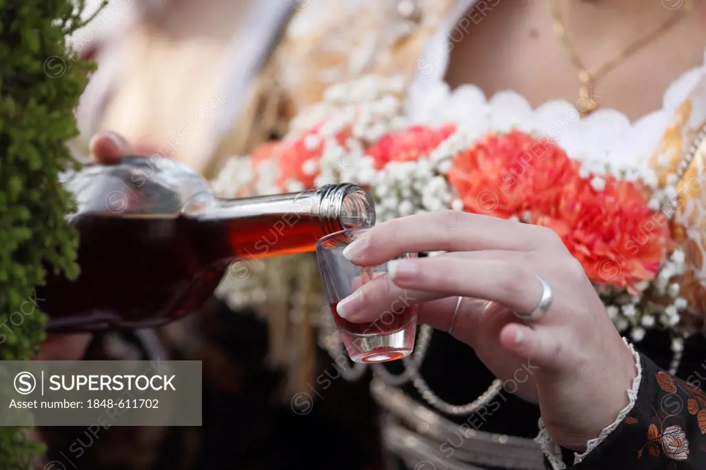 Woman pouring a shot of brandy, Leonhardi procession, Bad Toelz, Isarwinkel, Upper Bavaria, Bavaria, Germany, Europe