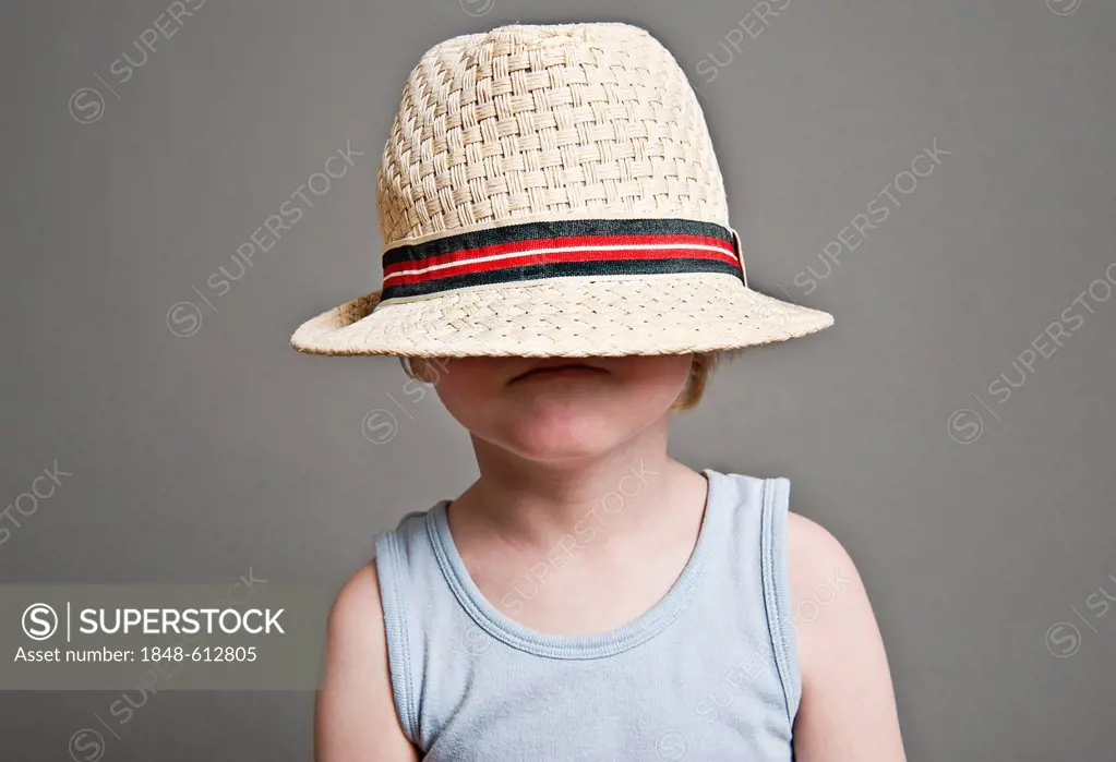 Little boy with large straw hat pulled over his head