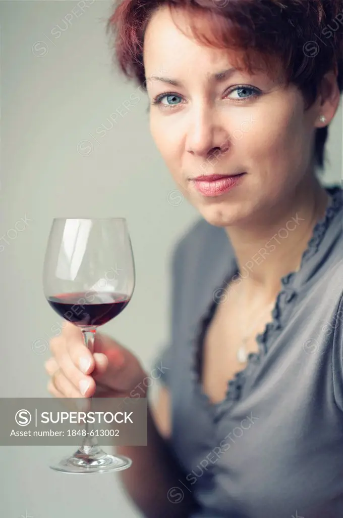 Smiling young woman with a glass of red wine