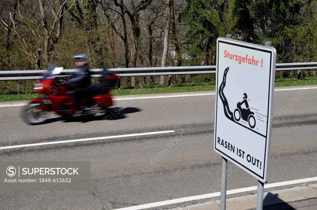 Motorcyclist on a country road with a warning sign, Sturzgefahr - Rasen ist out, German for dangerous curves - no speeding, Eifel, Germany, Europe