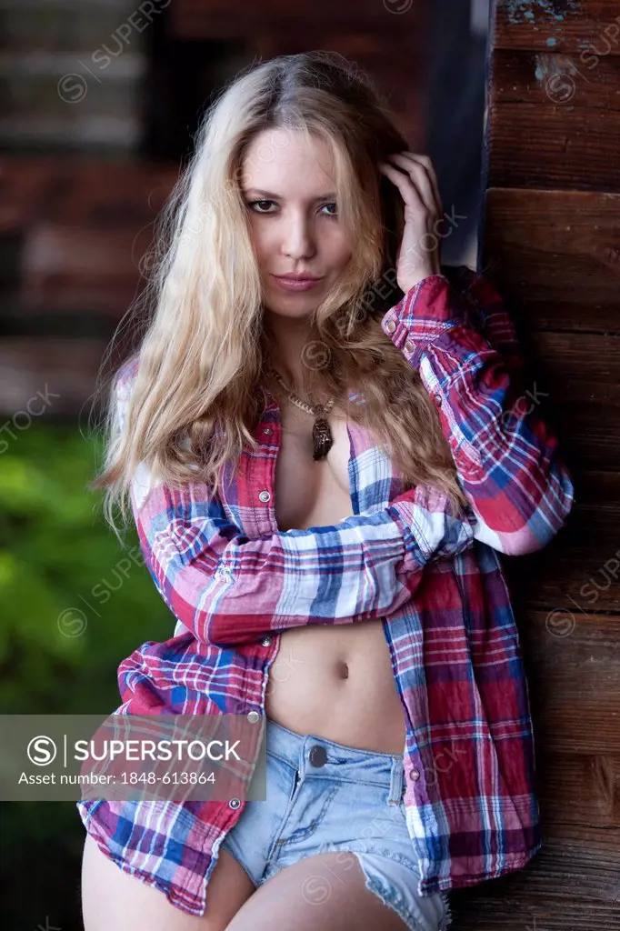 Young woman posing in denim hot pants and a plaid shirt