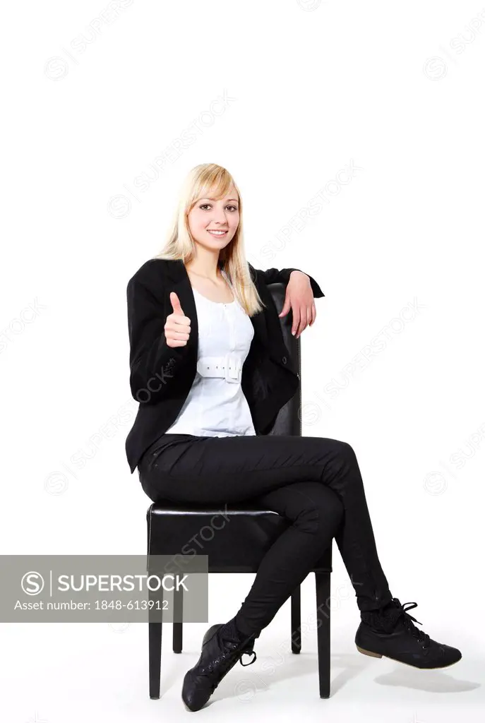 Young woman sitting on a chair, giving the thumbs up