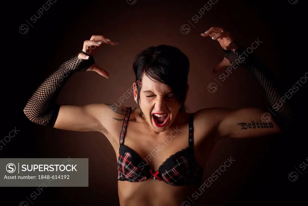 Woman, dressed in a Gothic style, wearing a bra and screaming