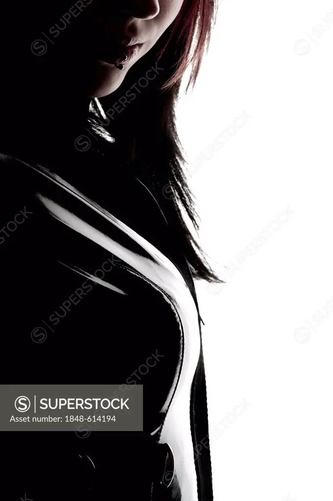 Woman, dressed in a Gothic style, with dark-haired pierced lips, wearing a latex suit, backlighting